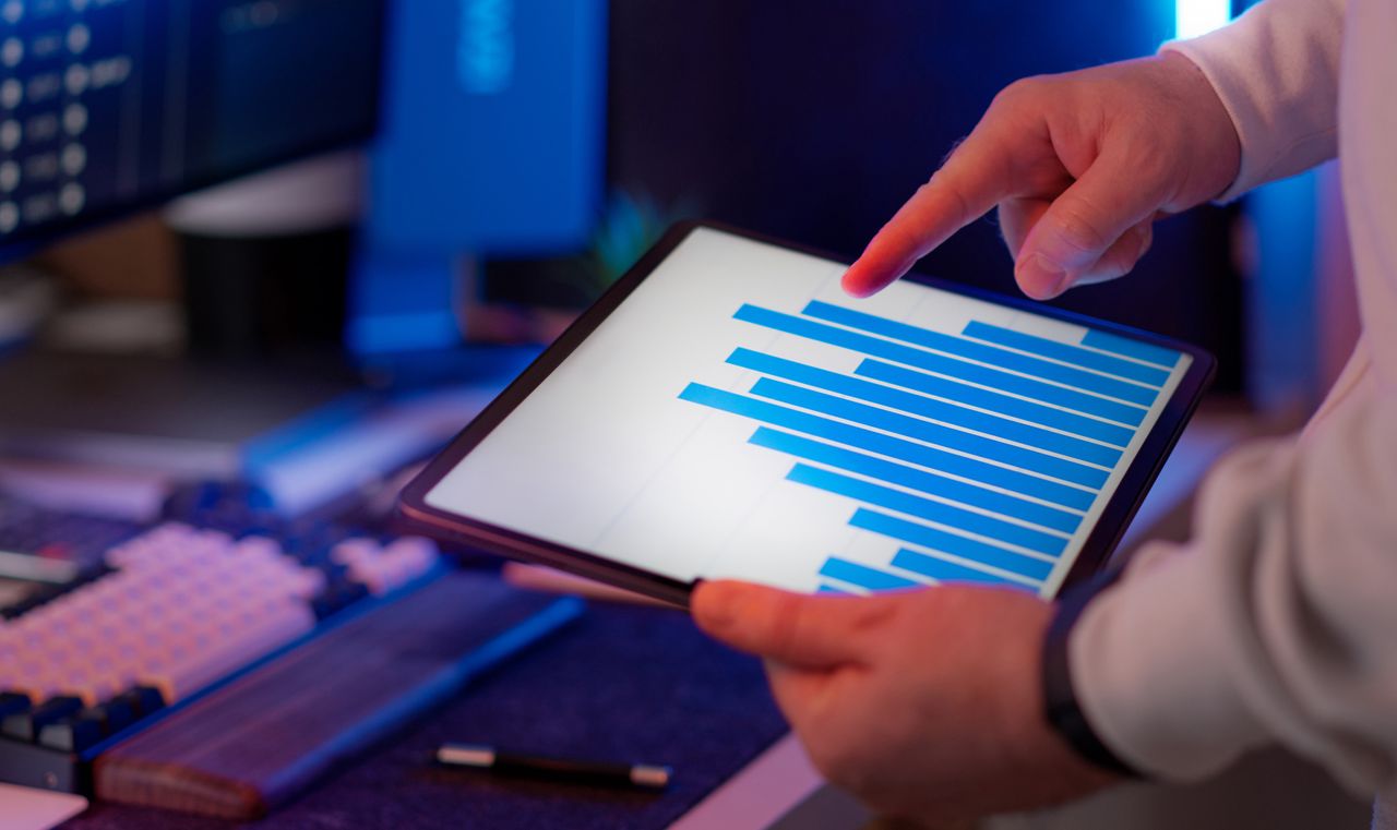 A professional analyzing stock market data on a laptop in a bright office environment.
